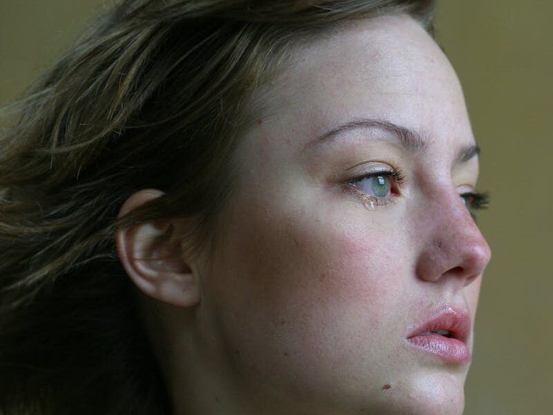 A young woman looks thoughtfully into the distance, capturing emotions with a side profile view.