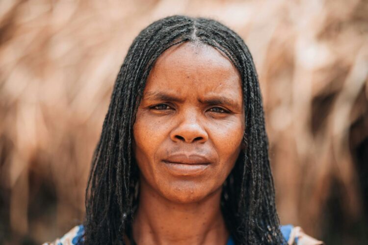 Close-up portrait of a woman with braided hair, expressing thoughtful emotion outdoors.