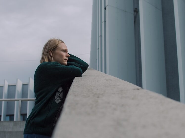 woman in black jacket standing near white concrete building during daytime
