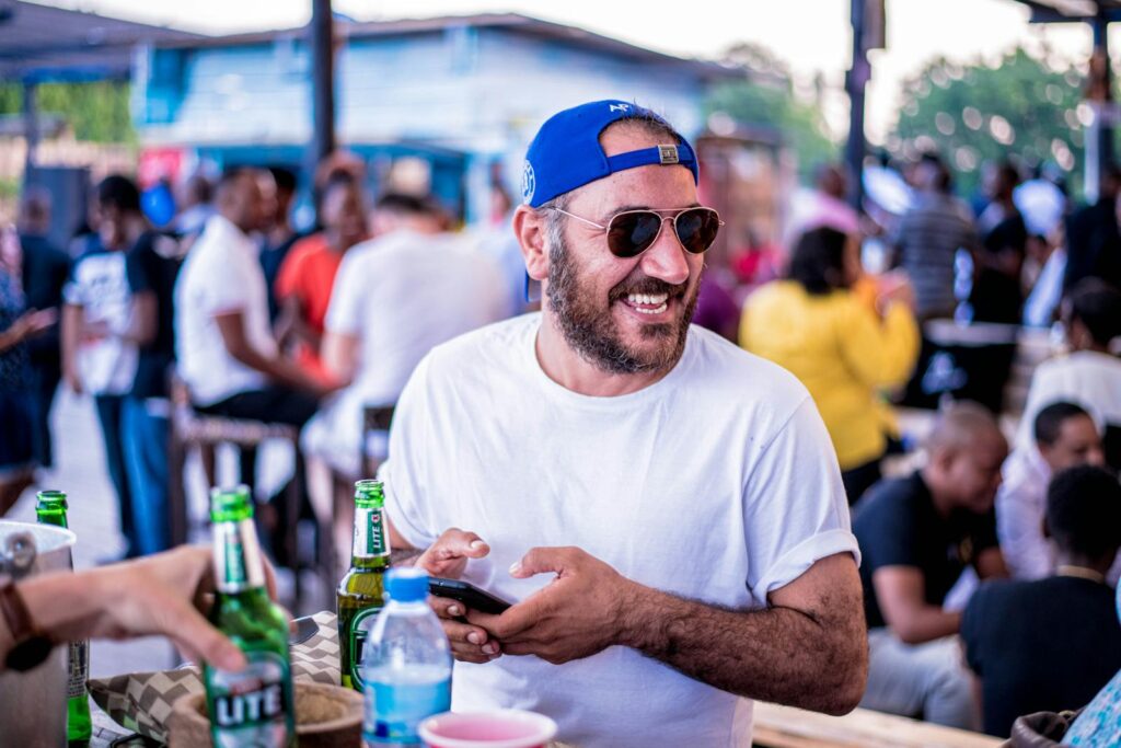 A cheerful man enjoying drinks at an outdoor gathering in Dar es Salaam, Tanzania.
