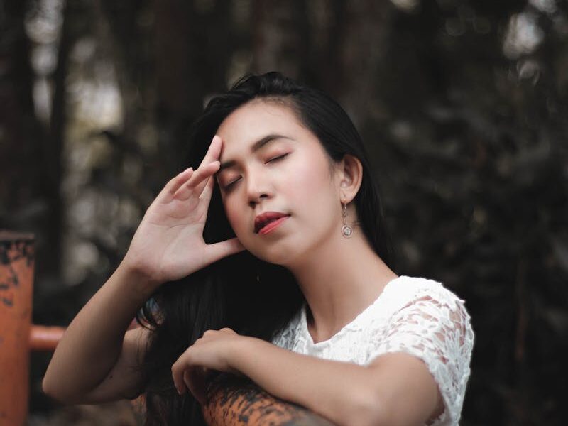 Peaceful portrait of a woman with closed eyes in a lush Bandung forest setting.