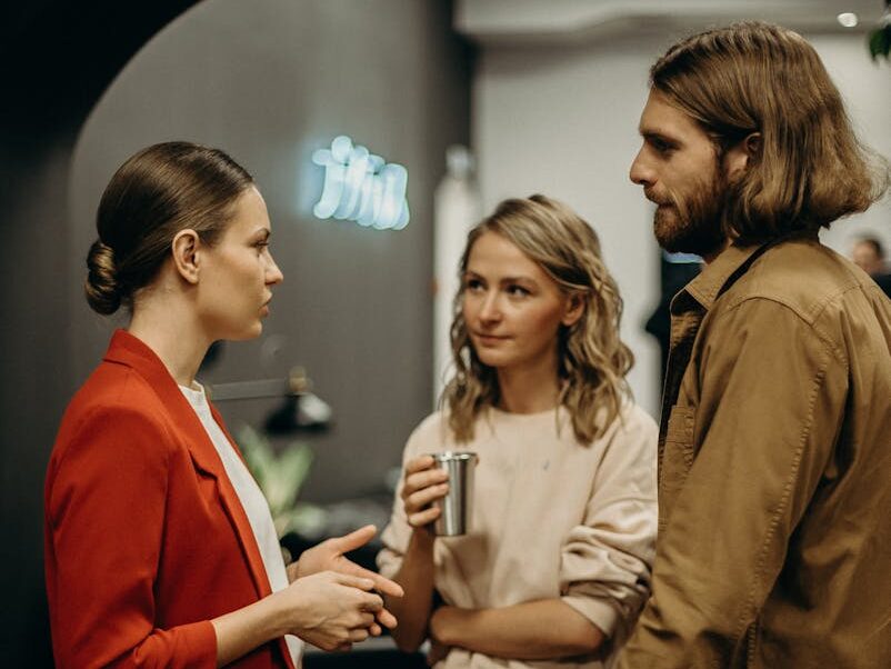 Three colleagues having a discussion in a modern office setting.