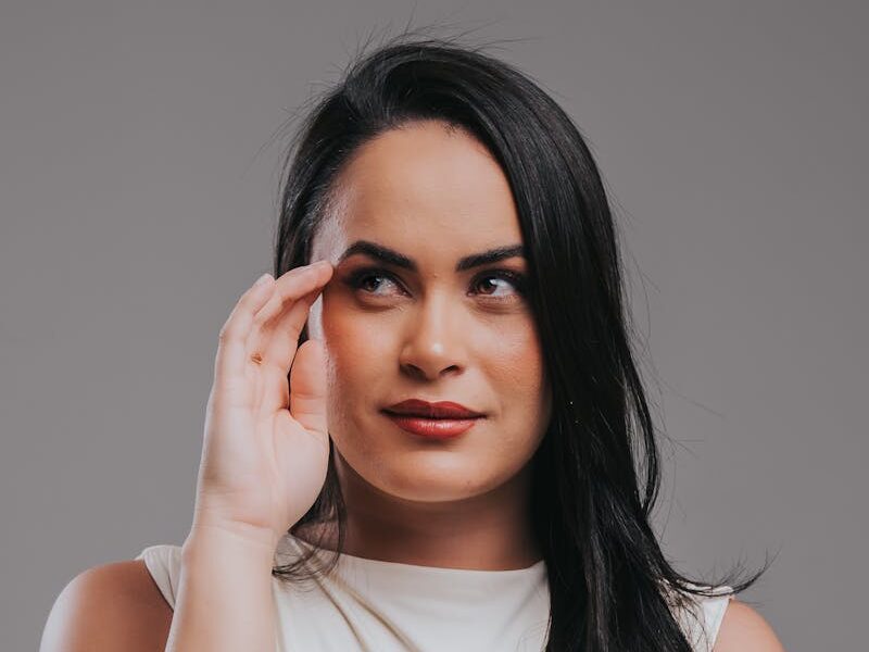 Portrait of a confident woman in a white top, appearing thoughtful and poised against a neutral background.