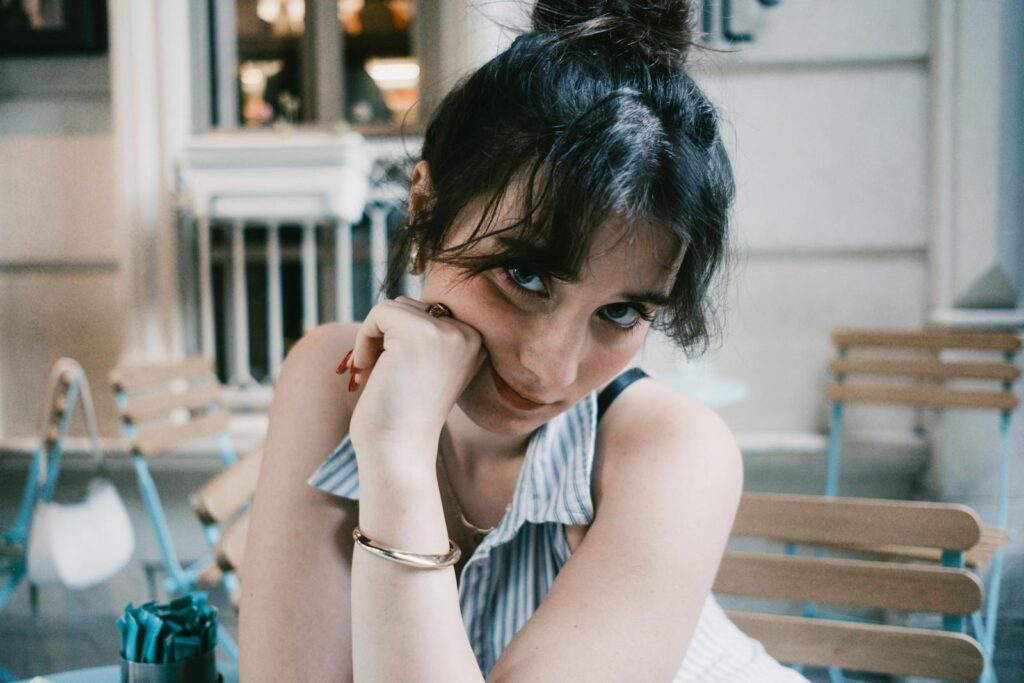 Young woman with a playful pose sitting at an outdoor café.