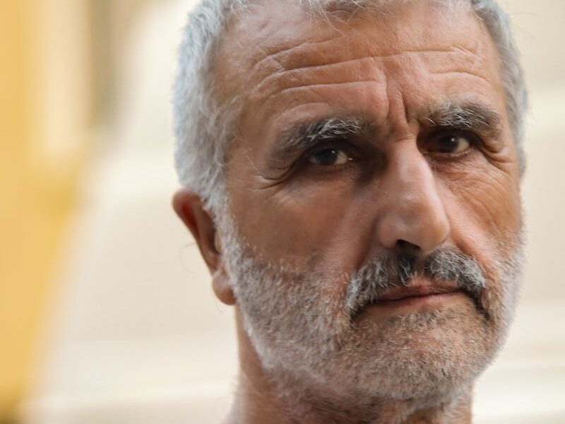 Close-up portrait of a senior adult man outdoors with a contemplative expression.