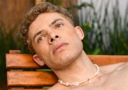Relaxed man sunbathing on wooden lounger in São Paulo garden setting.