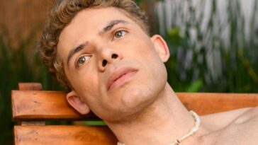 Relaxed man sunbathing on wooden lounger in São Paulo garden setting.