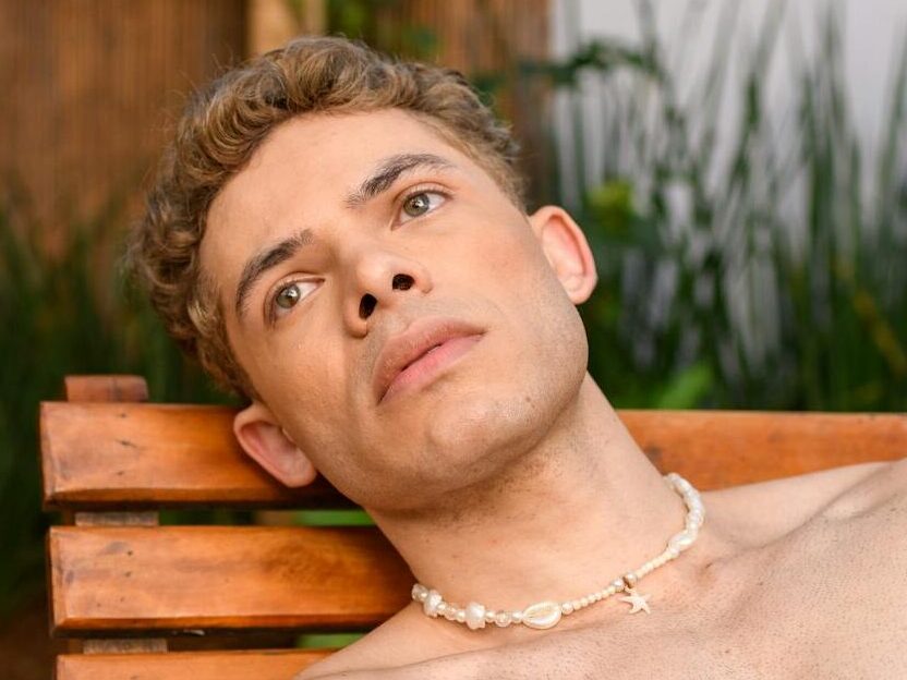 Relaxed man sunbathing on wooden lounger in São Paulo garden setting.