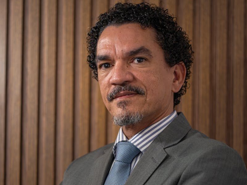 Confident businessman in a suit posing with arms crossed against wooden background.