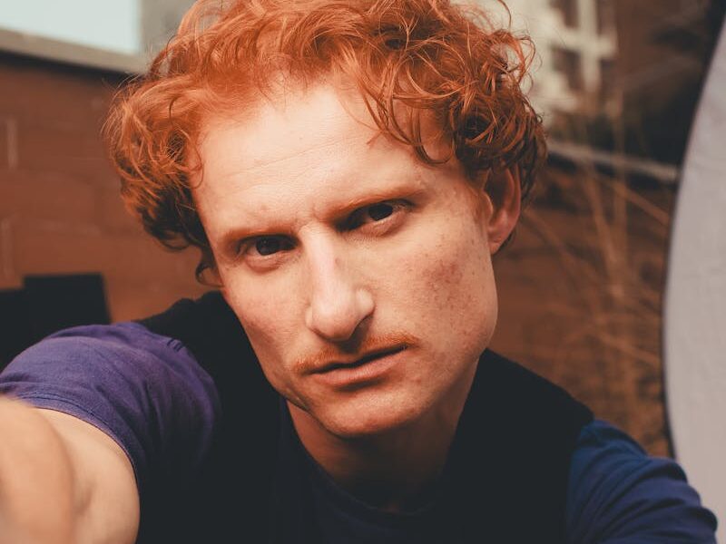 Close-up portrait of a red-haired man with an intense expression captured outdoors in São Paulo, Brazil.