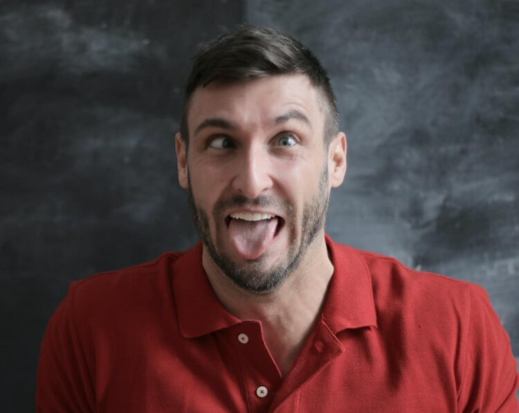 Funny portrait of a man making a silly face wearing a red polo shirt.