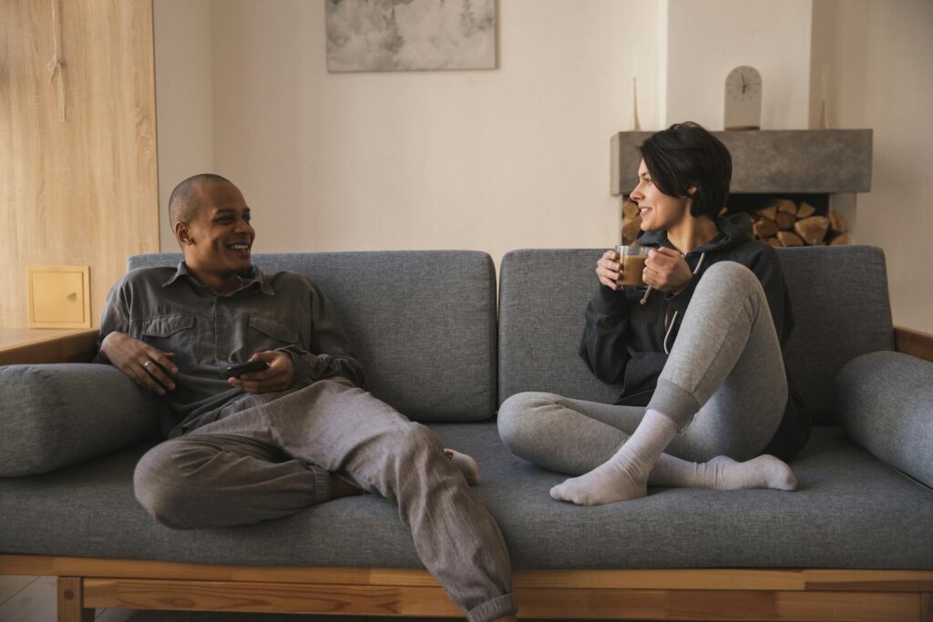 A cheerful couple enjoying coffee and conversation on a cozy sofa in a modern living room.