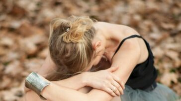 woman in black tank top and blue skirt sitting on dried leaves