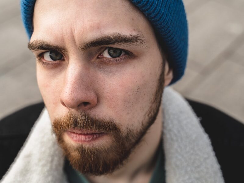 man in blue knit cap and green crew neck shirt