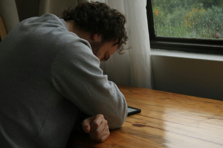 Man is looking at a screen with his head down.