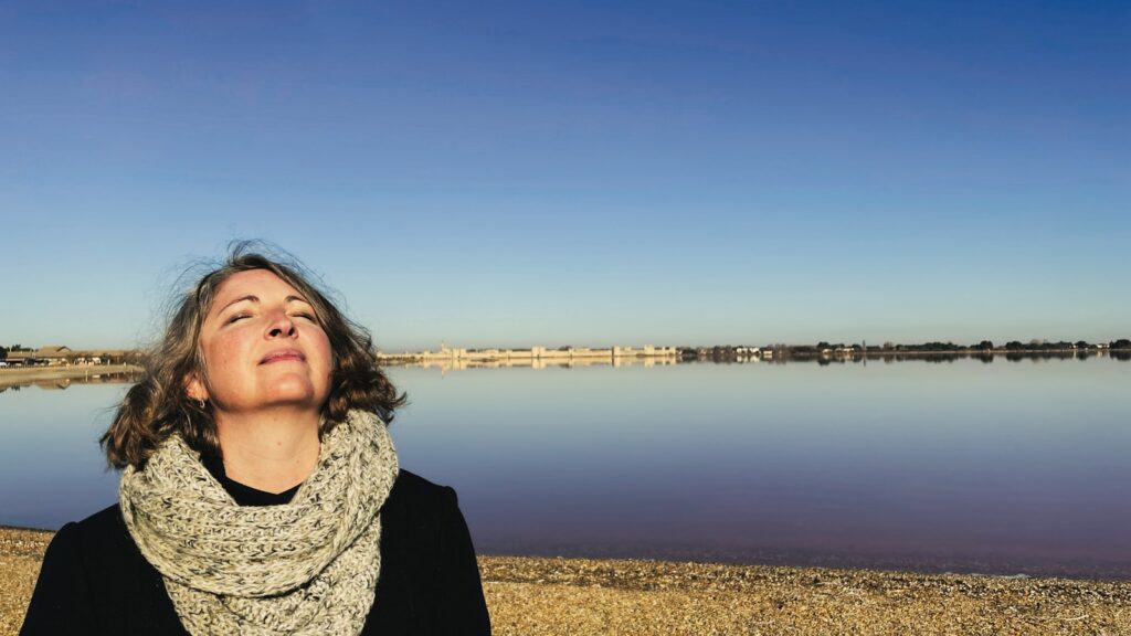 A woman standing on a beach looking up at the sky