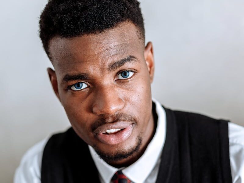 Portrait of an African American man in formal attire gesturing with confidence indoors.