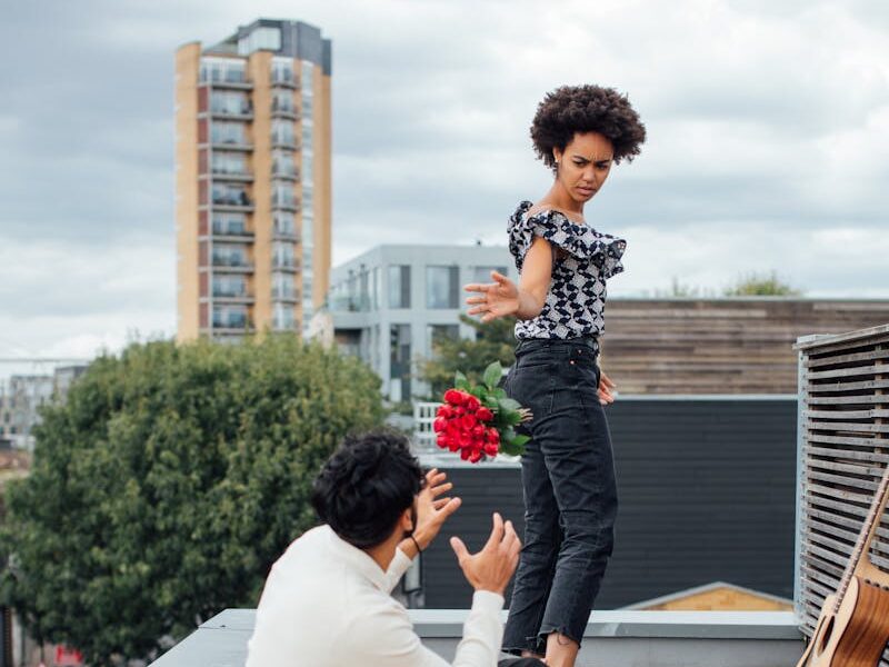 Interracial couple having a heated moment during a rooftop picnic. Emotional expressions.