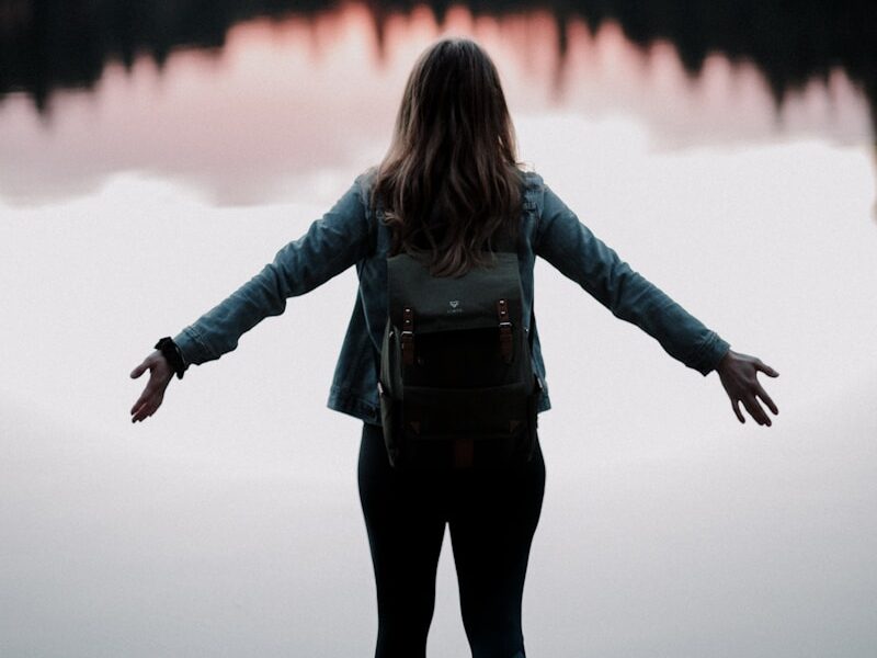 woman standing while facing on body of water