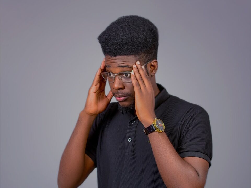 A man in a black shirt is holding his head