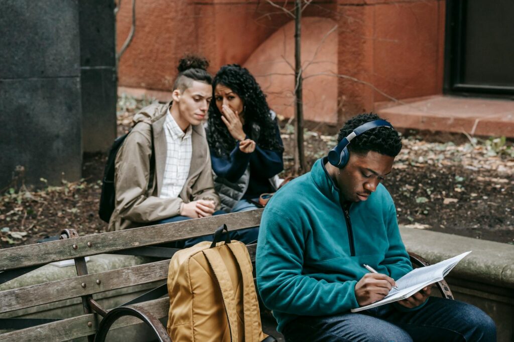 Diverse students studying and interacting on a university bench outdoors.