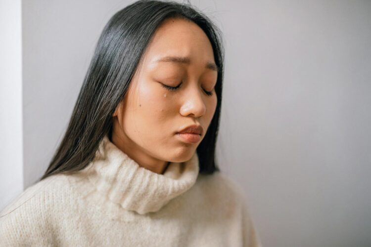 Close-up of an Asian woman with tears, showcasing emotional depth and sadness.