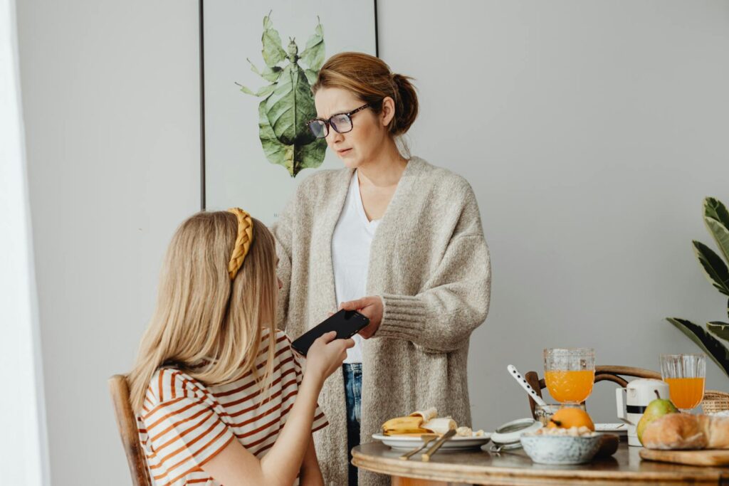 A mother correcting her teenage daughter's behavior during breakfast, conveying parenting dynamics.