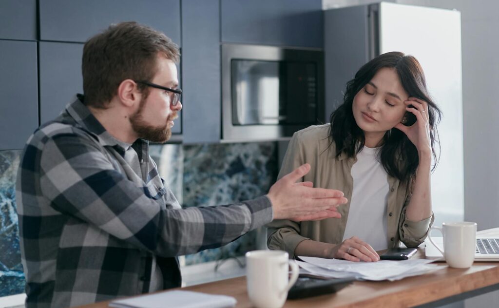 A couple engaging in a serious conversation in their kitchen, showcasing relationship dynamics.
