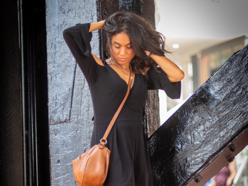 a woman in a short black dress is holding a purse
