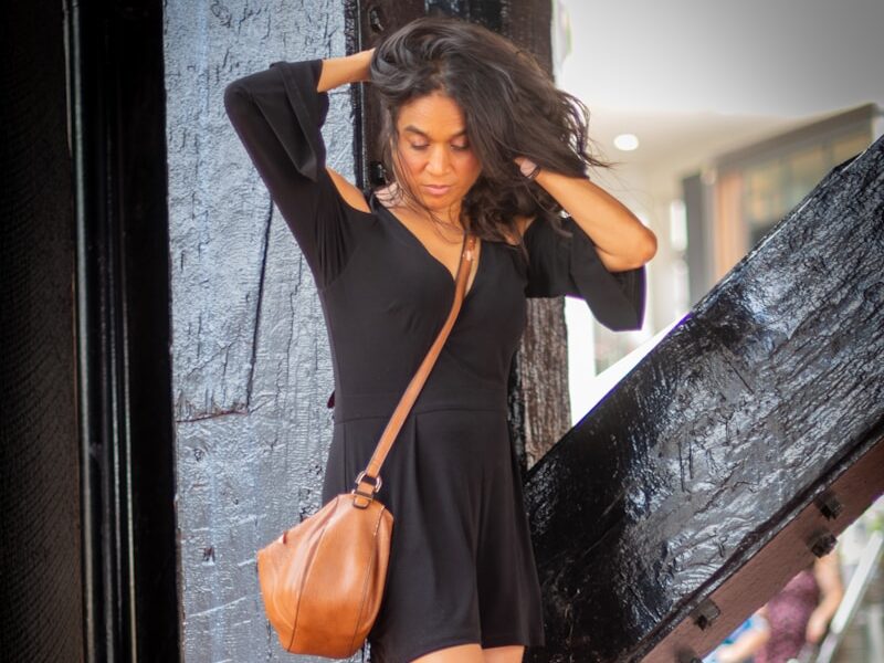 a woman in a short black dress is holding a purse