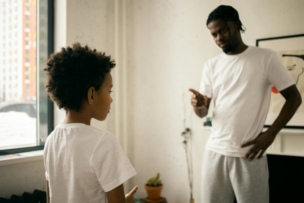 Father and young son having a serious discussion indoors with a focus on family dynamics.