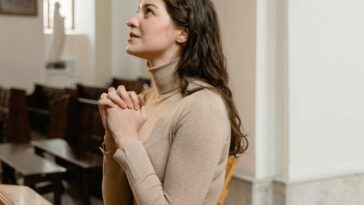 A woman deeply engaged in prayer inside a serene church setting, highlighting faith and spirituality.