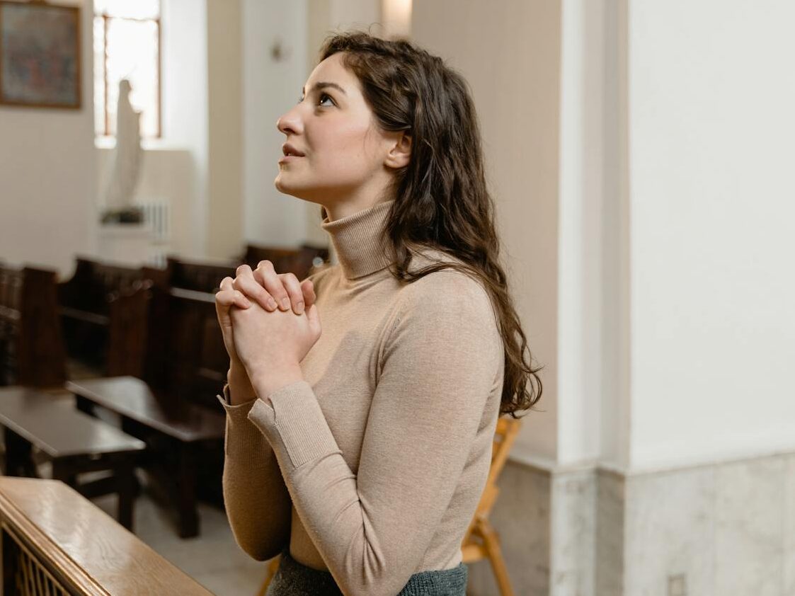 A woman deeply engaged in prayer inside a serene church setting, highlighting faith and spirituality.