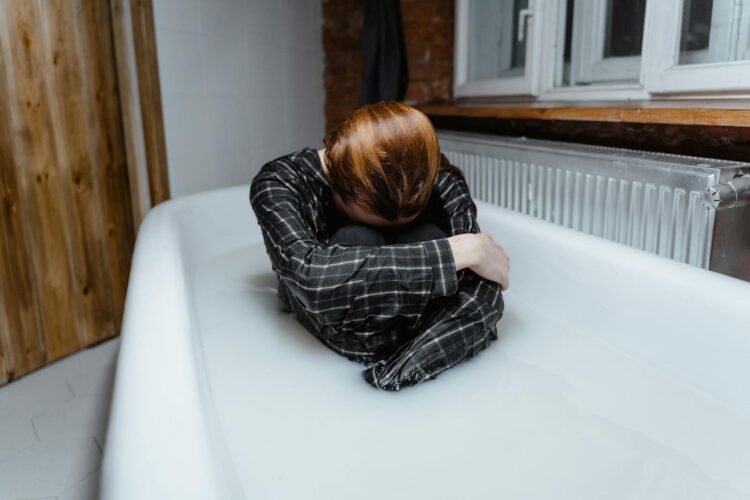 A person in a bathtub showing feelings of sadness and isolation, indoors.