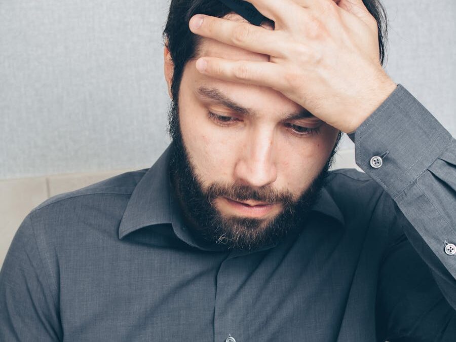 A stressed man looks at his smartphone, holding a credit card in his hand.