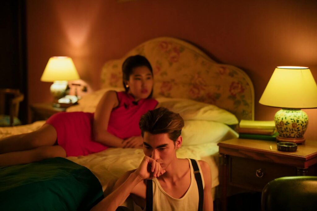 A couple in a warmly lit bedroom, reflecting on their relationship, creating a serene ambiance.