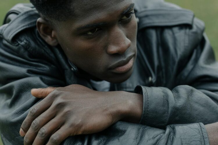 Expression of contemplation captured with a young man in a leather jacket outdoors.