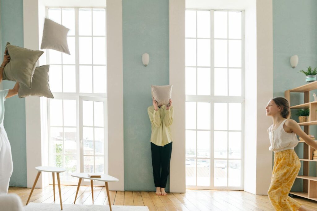 A joyful family enjoying a pillow fight in a bright and cozy living room.