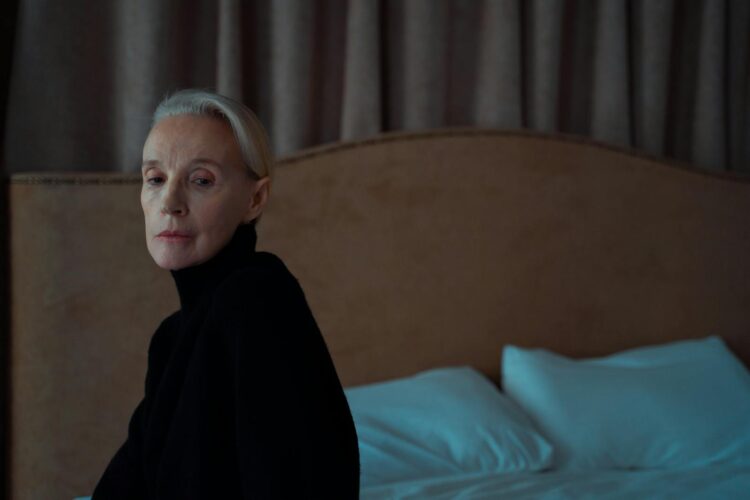 Senior woman in thoughtful solitude indoors on a bed.