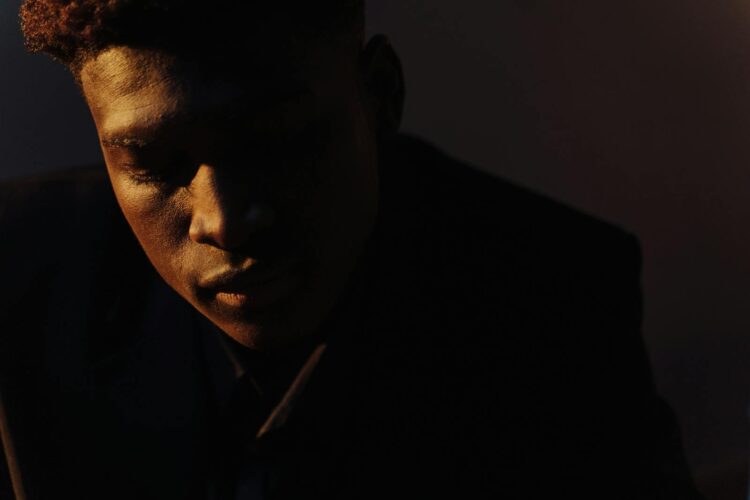 Close-up portrait of a man in dramatic lighting, conveying deep thought and introspection.
