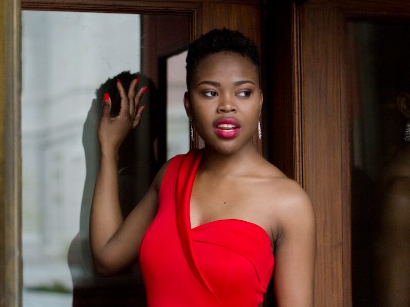 woman wearing red bodycon dress holding glass door