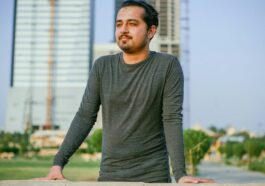a man leaning on a wall in front of a tall building