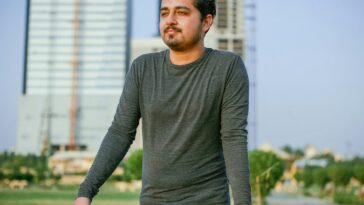a man leaning on a wall in front of a tall building
