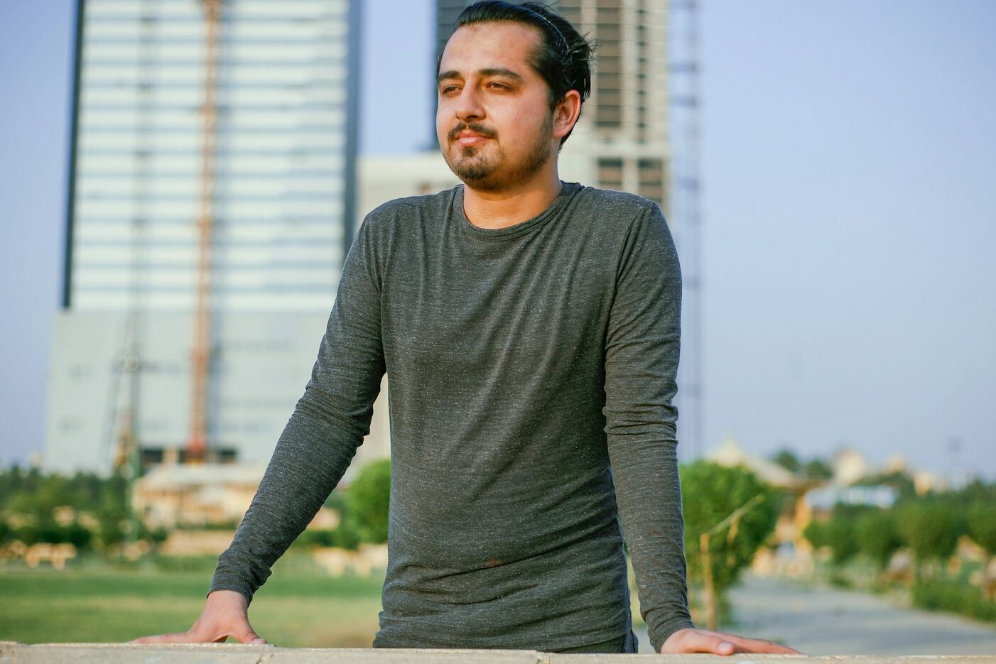 a man leaning on a wall in front of a tall building