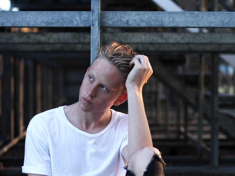 man sitting on floor wearing white crew-neck T-shirt