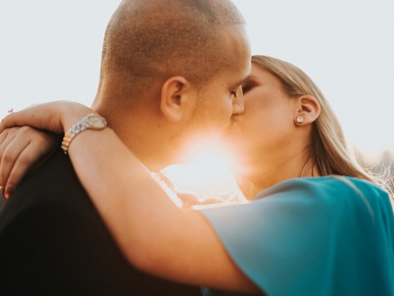 man in blue shirt kissing woman in black shirt