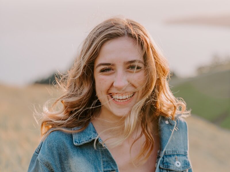 smiling woman sitting on grass during daytime