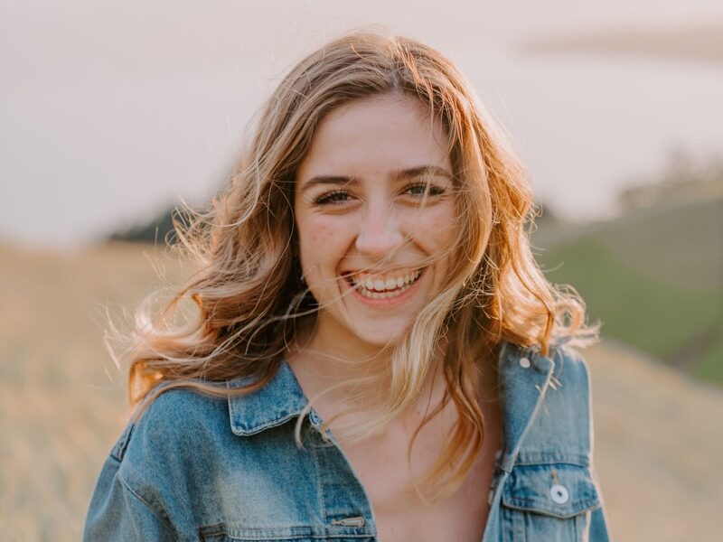 smiling woman sitting on grass during daytime