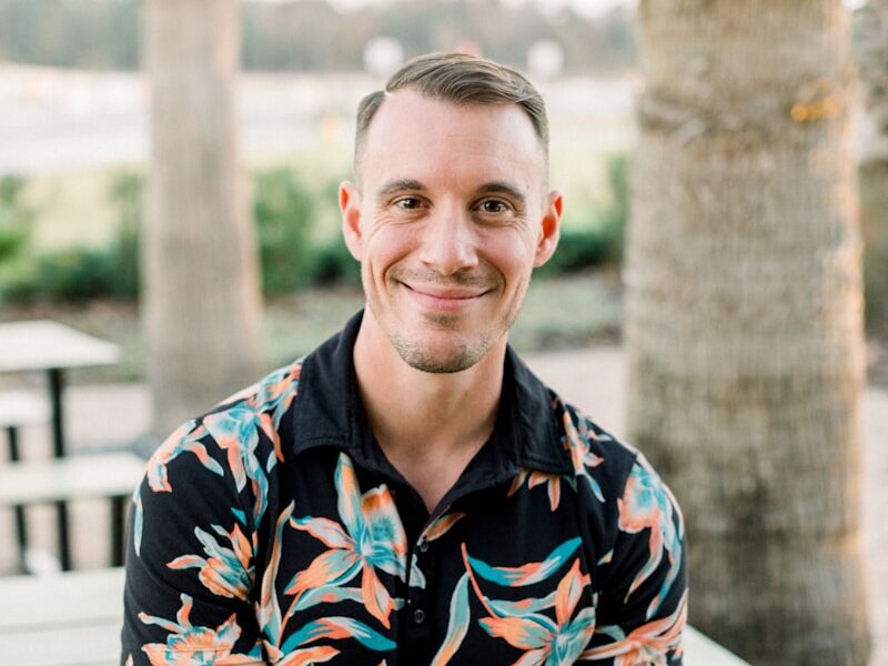a man sitting on a bench in front of palm trees