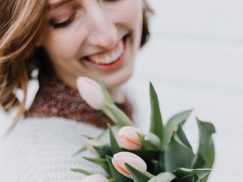 woman clutching bouquet of pink flowers and smiling